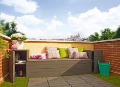 an outdoor seating area with green grass and brick walls