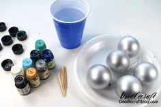 some silver balls are sitting on a white plate next to thread and paint bottles with pins