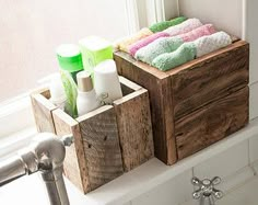 two wooden boxes with towels and soaps in them sitting on a bathroom sink next to a faucet