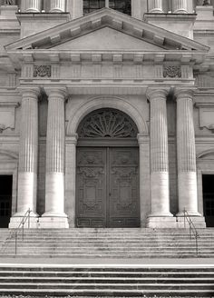 a black and white photo of an old building with steps leading up to the door