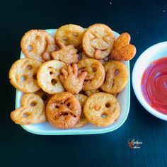 some fried food on a plate next to a bowl of ketchup