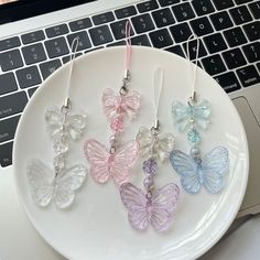 four butterfly shaped glass earrings are on a plate next to a laptop computer and keyboard