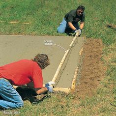 two men laying concrete on the ground