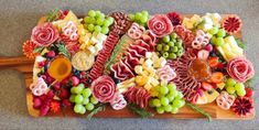 a wooden cutting board topped with lots of different types of fruit and veggies