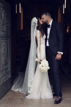 a bride and groom kissing in front of an ornate doorway