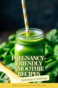 a green smoothie in a mason jar with a striped straw on top, surrounded by leafy greens