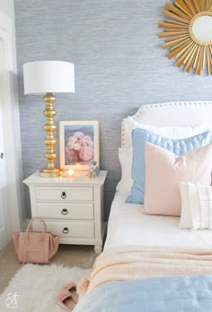 a bedroom with blue and white wallpaper, gold accents and a pink purse on the bed