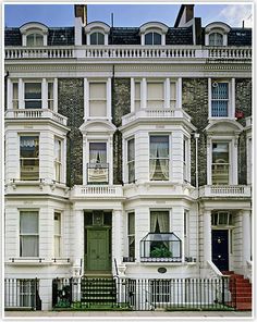 a large white building with many windows and balconies on the front, next to a black fence