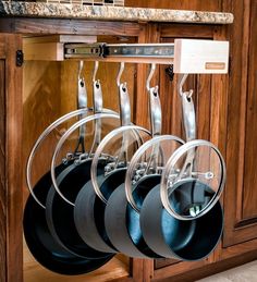 an image of pots and pans hanging on the rack in front of kitchen cabinets