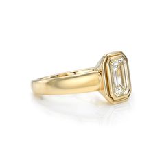 a yellow gold ring with an emerald stone in the center and two diamonds on each side