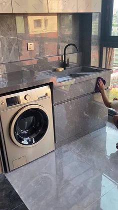 a woman is cleaning the kitchen floor with a rag and washing machine in front of her