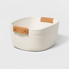 a white rope basket with leather handles