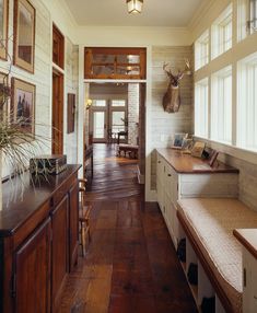 the interior of a house with wood floors and white brick walls, along with deer head mounted on the wall