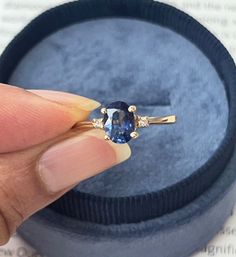 a woman's hand is holding an engagement ring with a blue stone in it