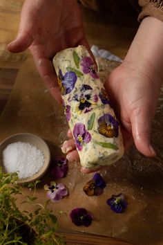 a person is holding something in their hand with flowers on it and some sugar next to them