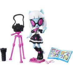 a doll with pink eyes and cat ears next to a camera, book and toy