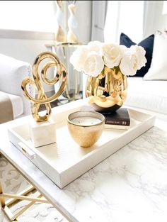 a white and gold coffee table with flowers in a glass vase on top of it