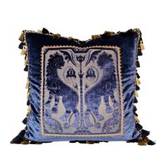 a blue and white pillow with tassels on the edges, in front of a white background