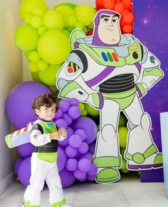 a young boy standing in front of a balloon wall with the character buzz lightyear