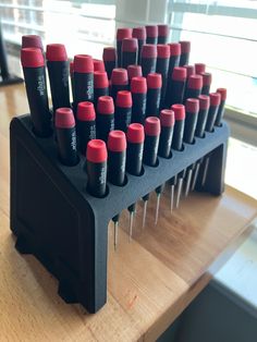 a bunch of red and black screwdrivers are on a wooden table next to a window