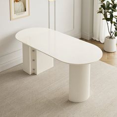 a large white table sitting in the middle of a room next to a potted plant