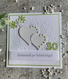 a card with two hearts on it and the number 30 written in german, surrounded by flowers