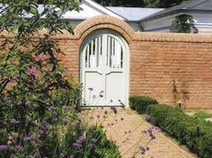 a brick wall with a white door surrounded by purple flowers