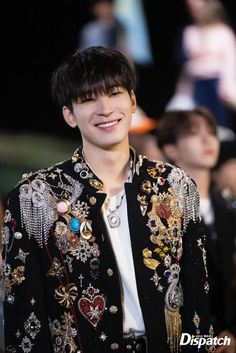 a young man wearing a black and gold jacket with lots of jewels on his chest