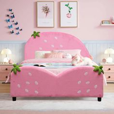 there is a pink bed with polka dots on it and two stuffed animals sitting on the headboard