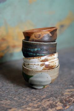 four stacked ceramic cups sitting on top of each other in front of a blue wall