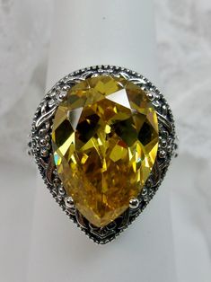 Simulated Yellow Citrine Gemstone Teardrop RingTear Vic Design#D28 Inspired by Victorian and Art Deco designs, this high-quality filigree ring is handcrafted in sterling silver. This teardrop ring is set with an 8 carat pear cut flawless yellow citrine simulated gemstone. The gem is 16mm (~5/8") x 12mm (~1/2"). The gorgeous stone has a lovely vibrant color. The inside of the band is marked 925 for sterling silver. Notice the beautiful filigree of the silver setting. This is a ring with beauty an Yellow Pear-shaped Gemstone Jewelry, Yellow Teardrop Ring For Formal Occasions, Yellow Teardrop Jewelry For Anniversary, Pear-shaped Yellow Ring For Gift, Yellow Teardrop Jewelry For Formal Occasions, Ornate Yellow Jewelry For Formal Occasions, Yellow Teardrop Wedding Ring, Yellow Teardrop Rings For Anniversary, Yellow Filigree Jewelry For Formal Occasions