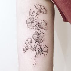 a black and white photo of a flower tattoo on the right arm, with leaves growing out of it