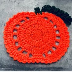 an orange crocheted dishcloth with black trim on top of a gray surface