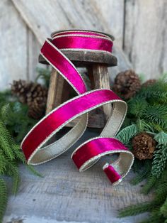 pink and silver ribbon with pine cones in the background