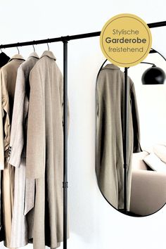 there is a coat rack with clothes hanging on it and a mirror in the background