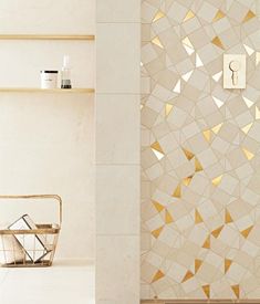 a bathroom with white and gold tiles on the wall, toiletries in basket next to it