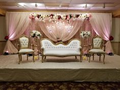 a stage set up with white couches and pink drapes