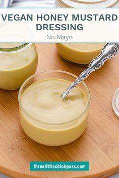 two small jars filled with vegan honey mustard sitting on top of a wooden cutting board