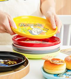 a person holding a yellow frisbee in front of some plates