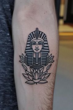 Tattoo of an Egyptian pharaoh's head with lotus flowers below on a forearm. Pharaoh Tattoo Stencil, Simple Egyptian Tattoo, Pharaoh Tattoo Design, Tutankhamun Tattoo, Egyptian King Tattoo, King Tut Tattoo Design, Egyptian Theme Tattoo, King Tut Tattoo, Pharaoh Tattoo