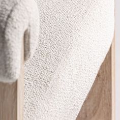 a white towel hanging on the side of a wooden rack with two towels in it