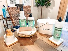 a wooden table topped with lots of cleaning products next to a basket filled with towels