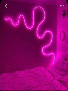 a bed in a room with pink lights on the headboard and wall behind it