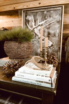 a table topped with books next to a basket filled with pine cones and an antelope