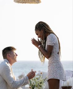 a man and woman standing next to each other at a table with flowers on it