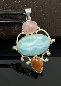 Larimar, Morganite and Sunstone Gemstone Sterling Silver Pendant Jewelry at Wholesale Price. SIZE : 2.65” X 1.75” ( including Bail) ( LXW ) *Width mentioned is at its widest * WEIGHT : 23.6g GEMSTONE : NATURAL MORGANITE, LARIMAR AND SUNSTONE TREATMENT: NO TREATMENT METAL : 925 STERLING SILVER HANDMADE **All Measurements are close approximations** LARIMAR : Larimar is the embodiment of the tranquil Sea and Sky energies. Its soft, soothing blues and calming turquoise is streaked with white pattern San Ramon, Silver Jewelry Pendant, Pendant Silver, Wrapped Pendant, Wire Wrapped Pendant, Bohemian Jewelry, Morganite, Sterling Silver Pendant, Gemstone Pendant