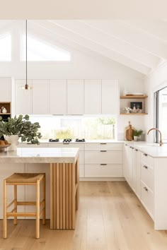 a kitchen with white cabinets and an island in the middle, along with wooden stools