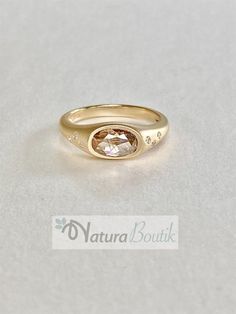 a yellow gold ring with an oval shaped stone in the center and small diamonds around it