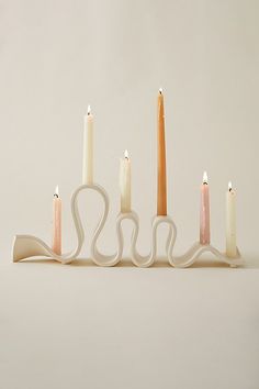 five candles are lined up in the shape of a long, curved candle holder with four smaller ones on each side