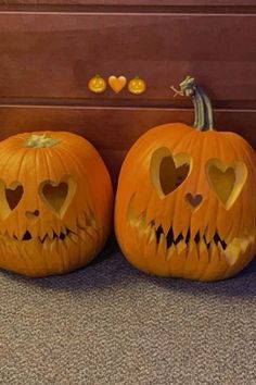 two carved pumpkins with faces and hearts on them